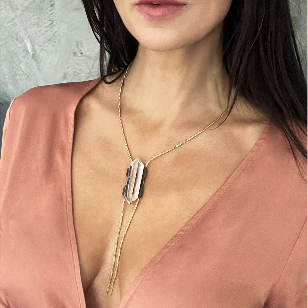 Close-up of woman in salmon top with modern necklace pendant.