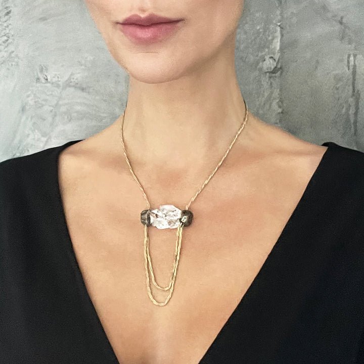 Close-up of person in black clothing wearing modern crystal necklace.