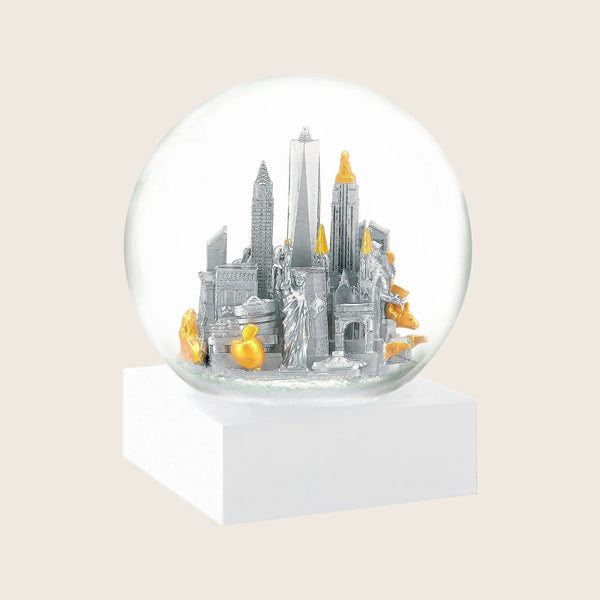 Snow globe with stylized urban skyline, gold and silver accents.