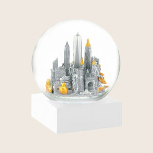 Snow globe with stylized urban skyline, gold and silver accents.