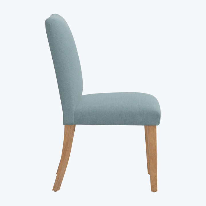Modern dining chair with light blue fabric upholstery and wood legs.
