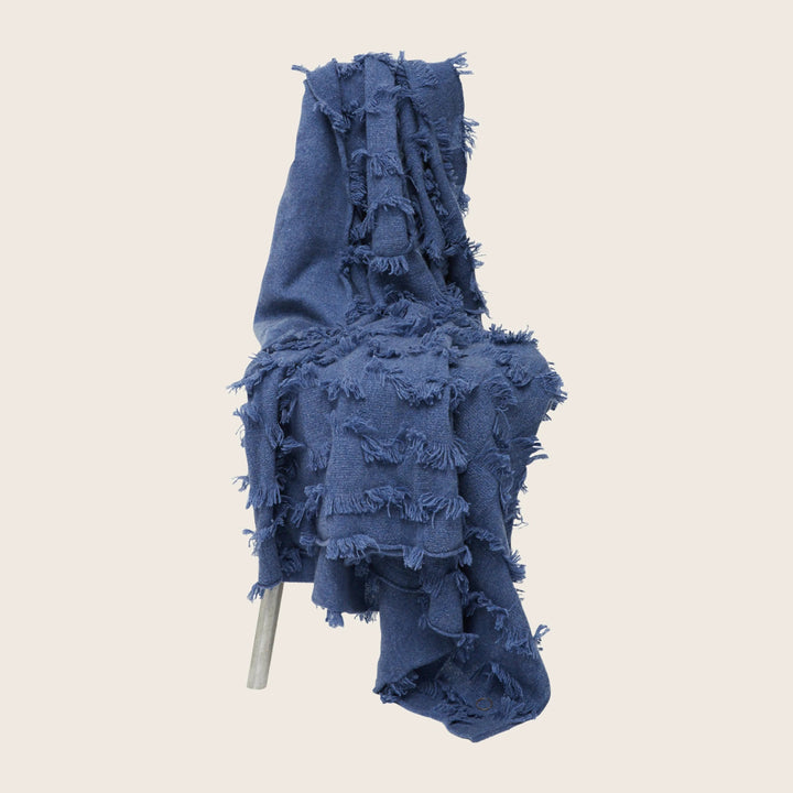 Deconstructed denim garment with extensive distressing and fraying details.