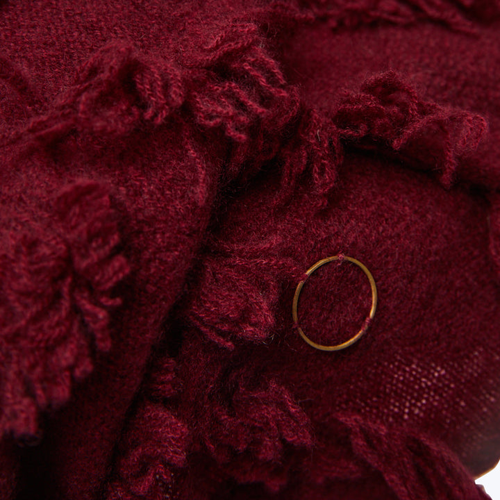 Close-up of dark red fluffy fabric with gold ring detail.