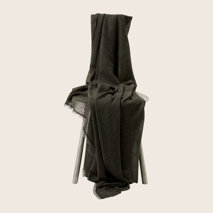 Dark gray blanket draped over four-legged stool for cozy decor.