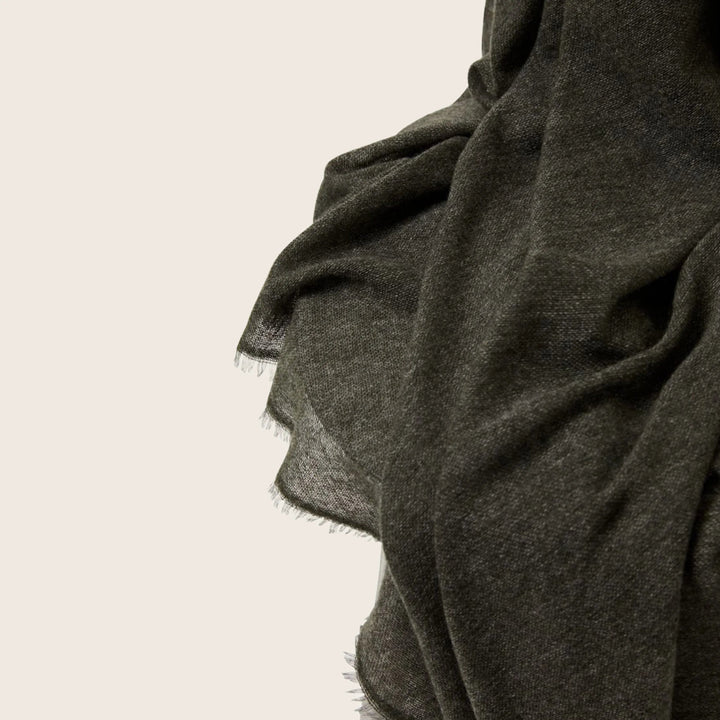 Close-up of textured dark gray fabric with frayed edges.