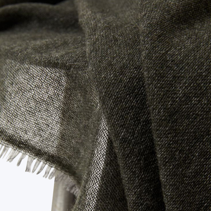 Close-up of dark gray woolen fabric with fringe, textured weave.