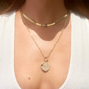 Close-up of person wearing celestial-themed gold choker and pendant necklaces.