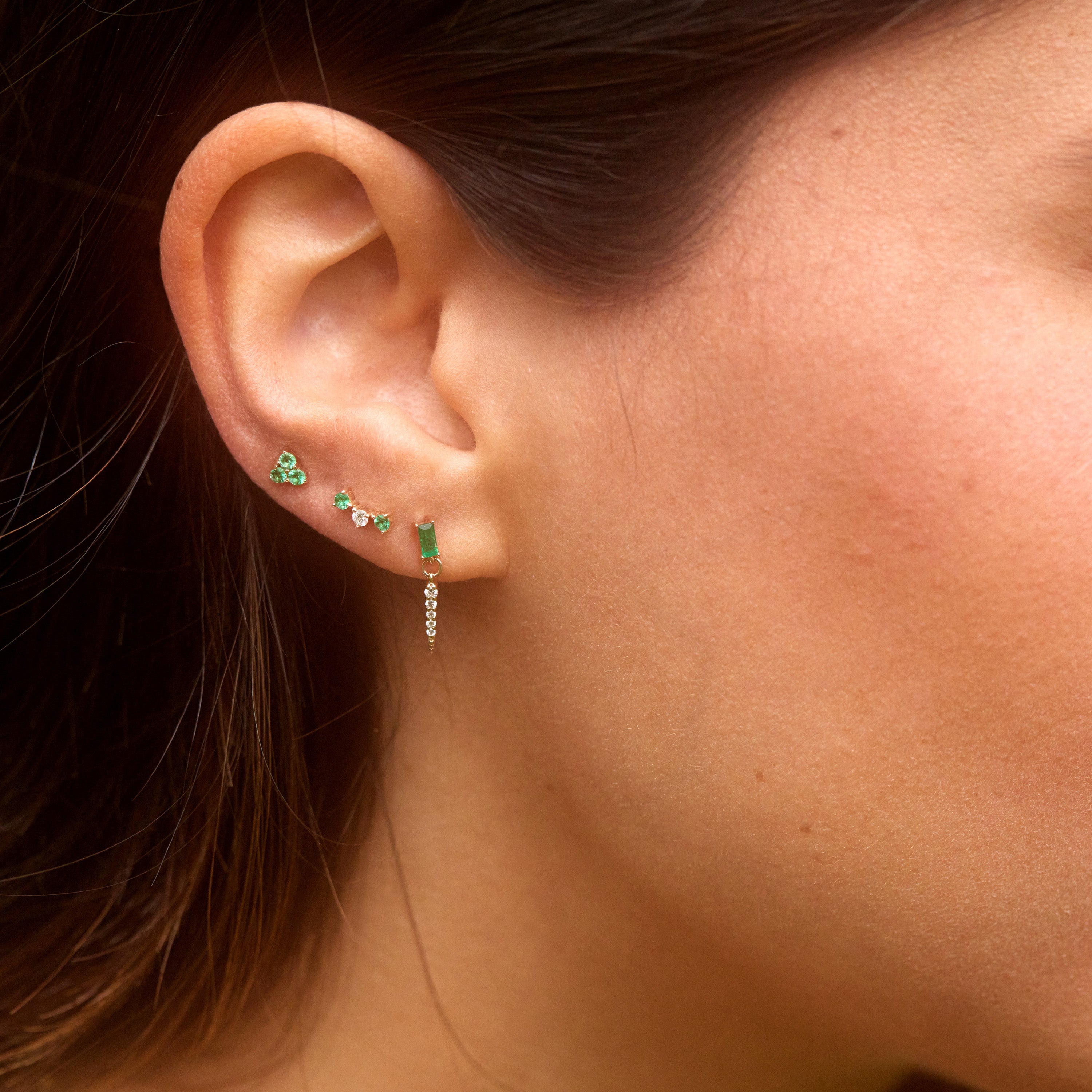 Elegant ear adorned with coordinated green gemstone earrings in close-up.