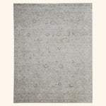 Rectangular area rug with faded, distressed traditional pattern in neutrals.