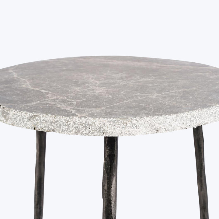 Modern circular stone tabletop table with black metal tapered legs.