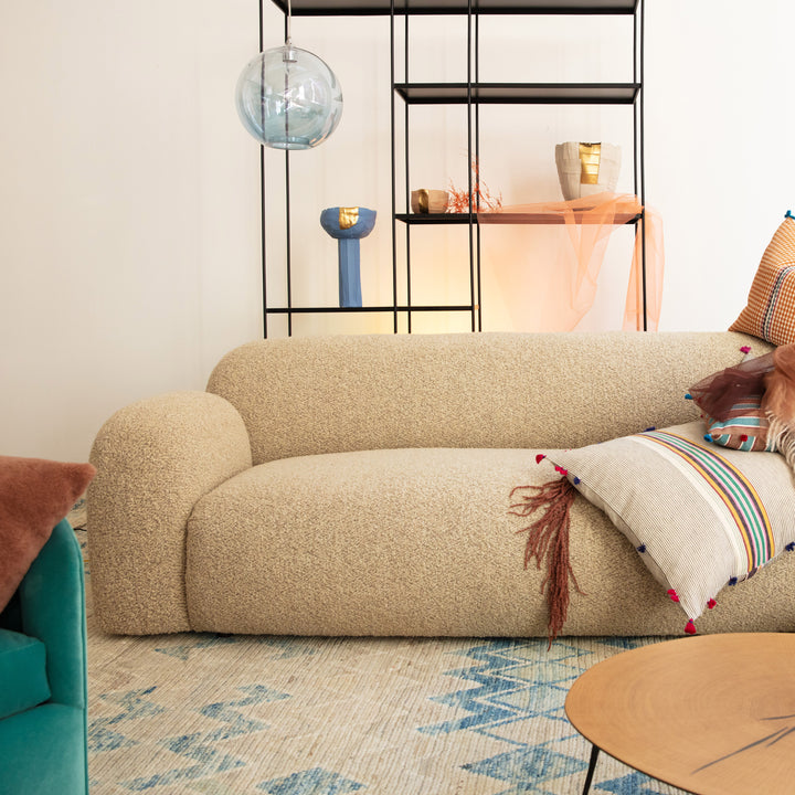 Cozy modern living room with beige sofa, teal armchair, and textures.