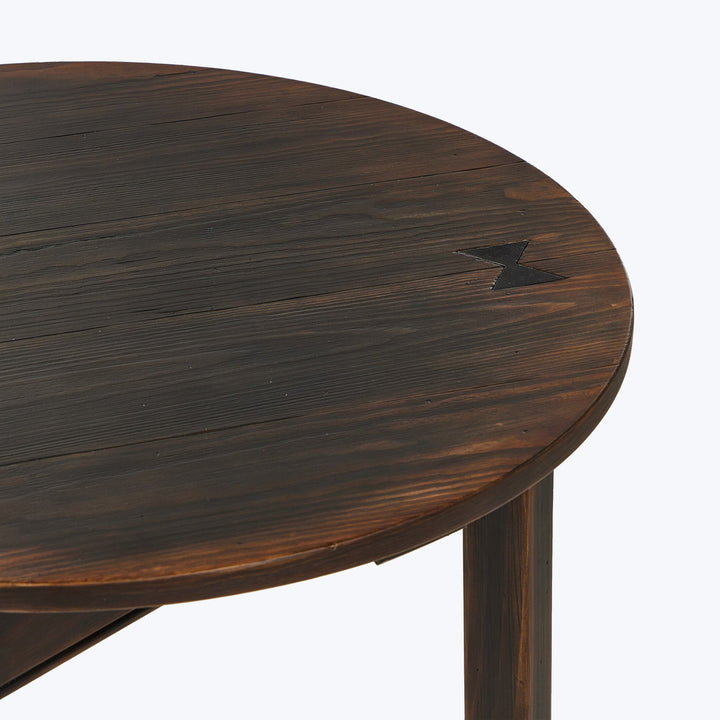 Round dark-stained wooden table with tree-inspired design detail.