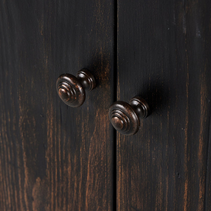 Close-up of elegant wooden cabinet with antique metallic knobs.