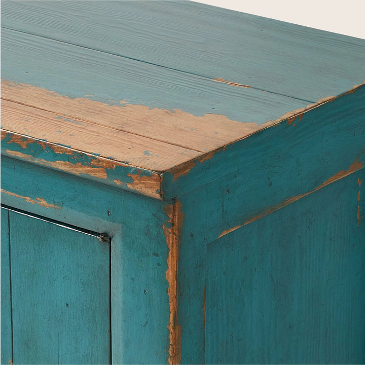 Close-up of vintage teal wooden furniture with chipped paint detail.