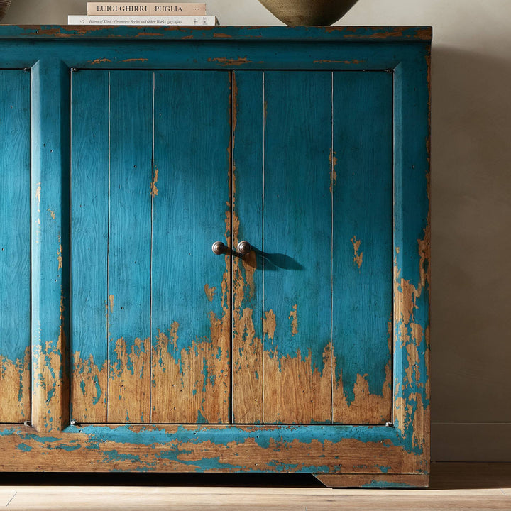 Vintage distressed turquoise cabinet with book on top, rustic charm.