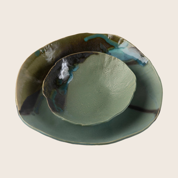 Handcrafted ceramic plate with unique green glazing and metallic sheen.