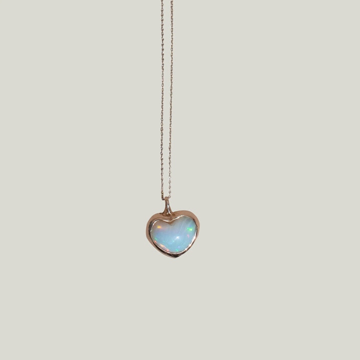 Golden heart pendant with opalescent stone on chain, elegant jewelry