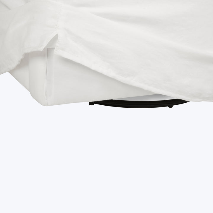 White cloth draped over black round object on floor. Wrinkled.