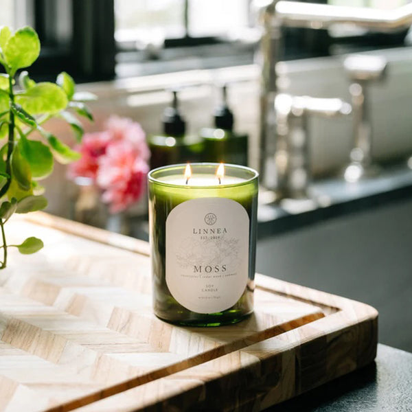 LIT LINNÉA MOSS scented candle on wooden tray in bathroom