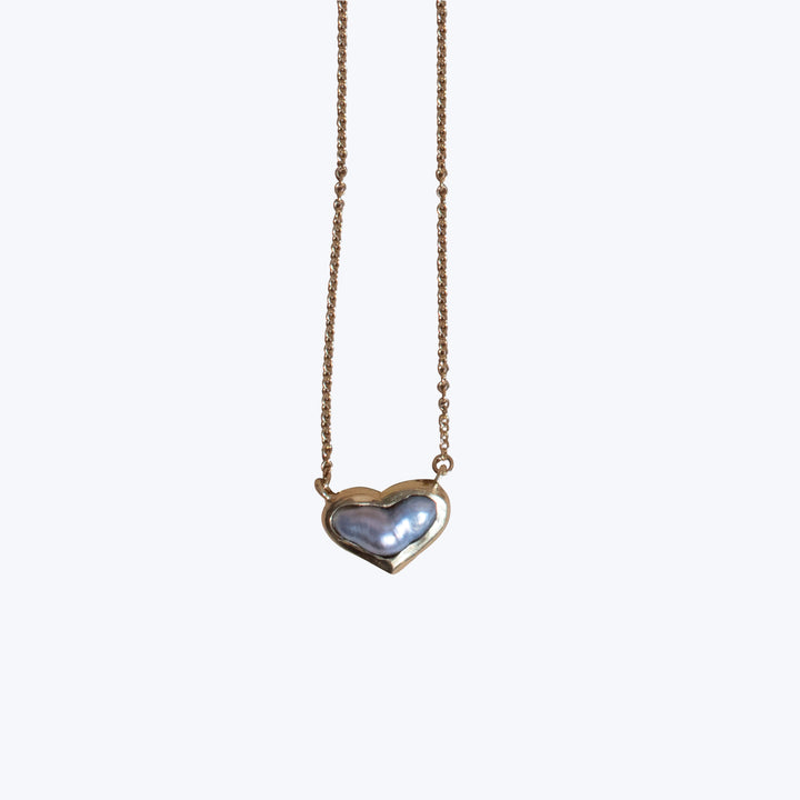 Elegant heart-shaped pendant necklace with iridescent pearl, gold-toned setting.