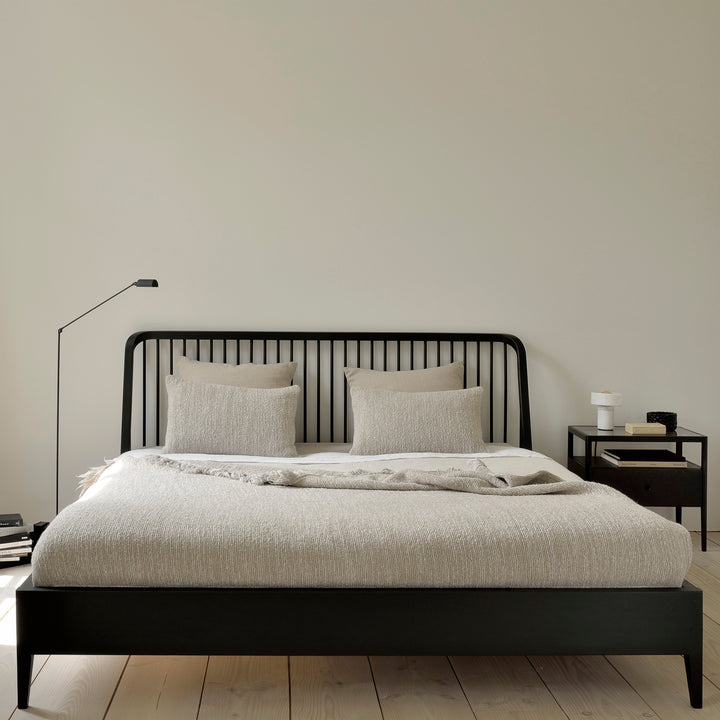 Minimalist bedroom with black accents, textured bedding, and cozy lighting.