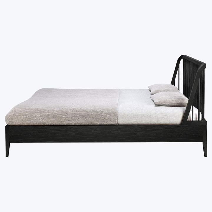 Modern black bed frame with beige bedding and matching pillows.