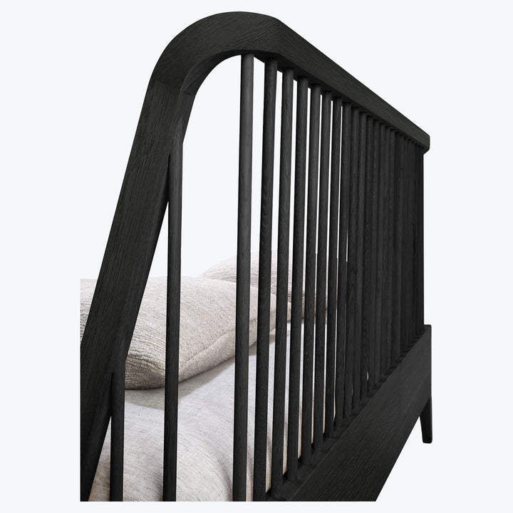 Close-up of black wooden crib with arched headboard slats.