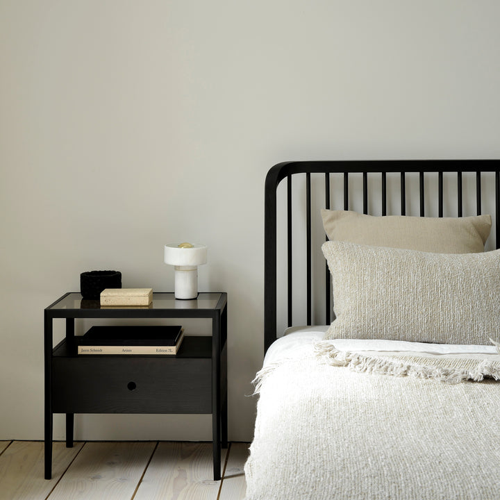 Minimalistic bedroom with black bed frame, nightstand, and decor items.