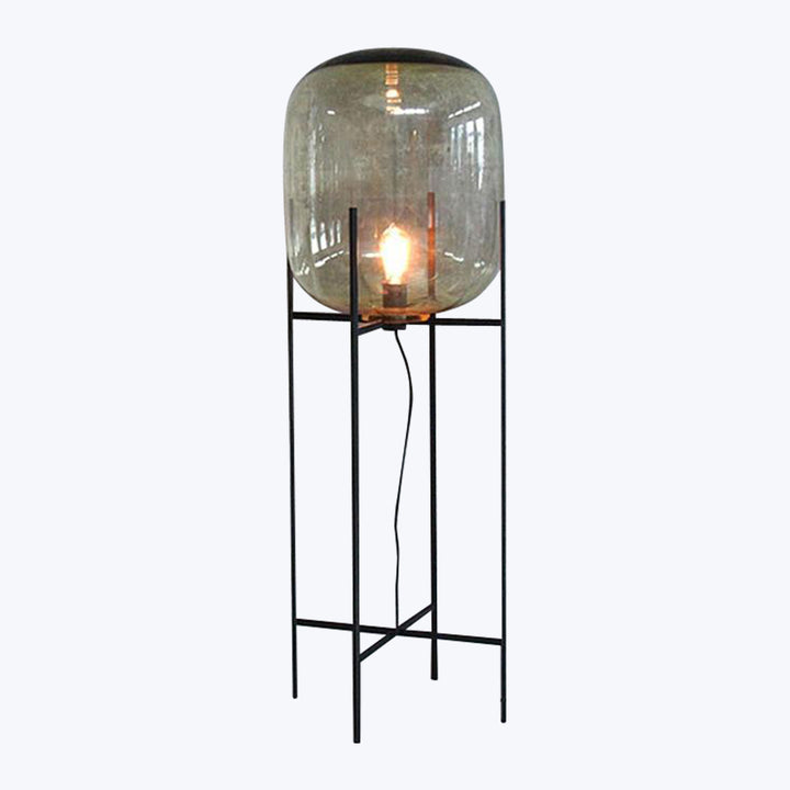 Modern floor lamp with rounded glass shade emits warm glow.