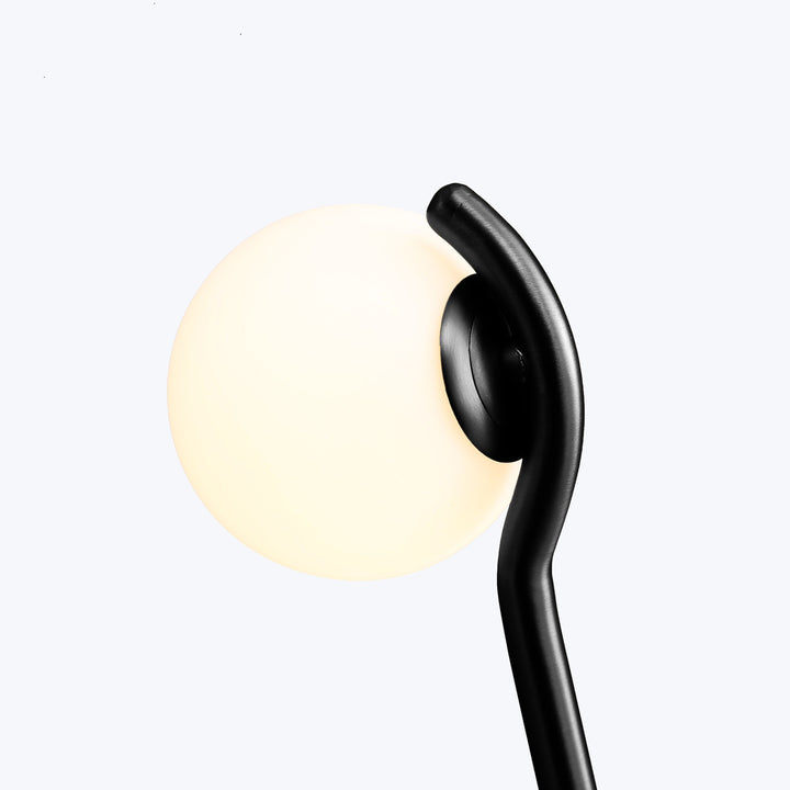 Black wireless earphone against glowing frosted glass orb, minimalist design