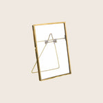Empty standing photo frame with golden border and back stand.