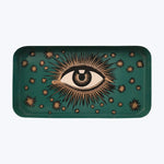 Golden eye illustration on teal tray with starburst patterns background.