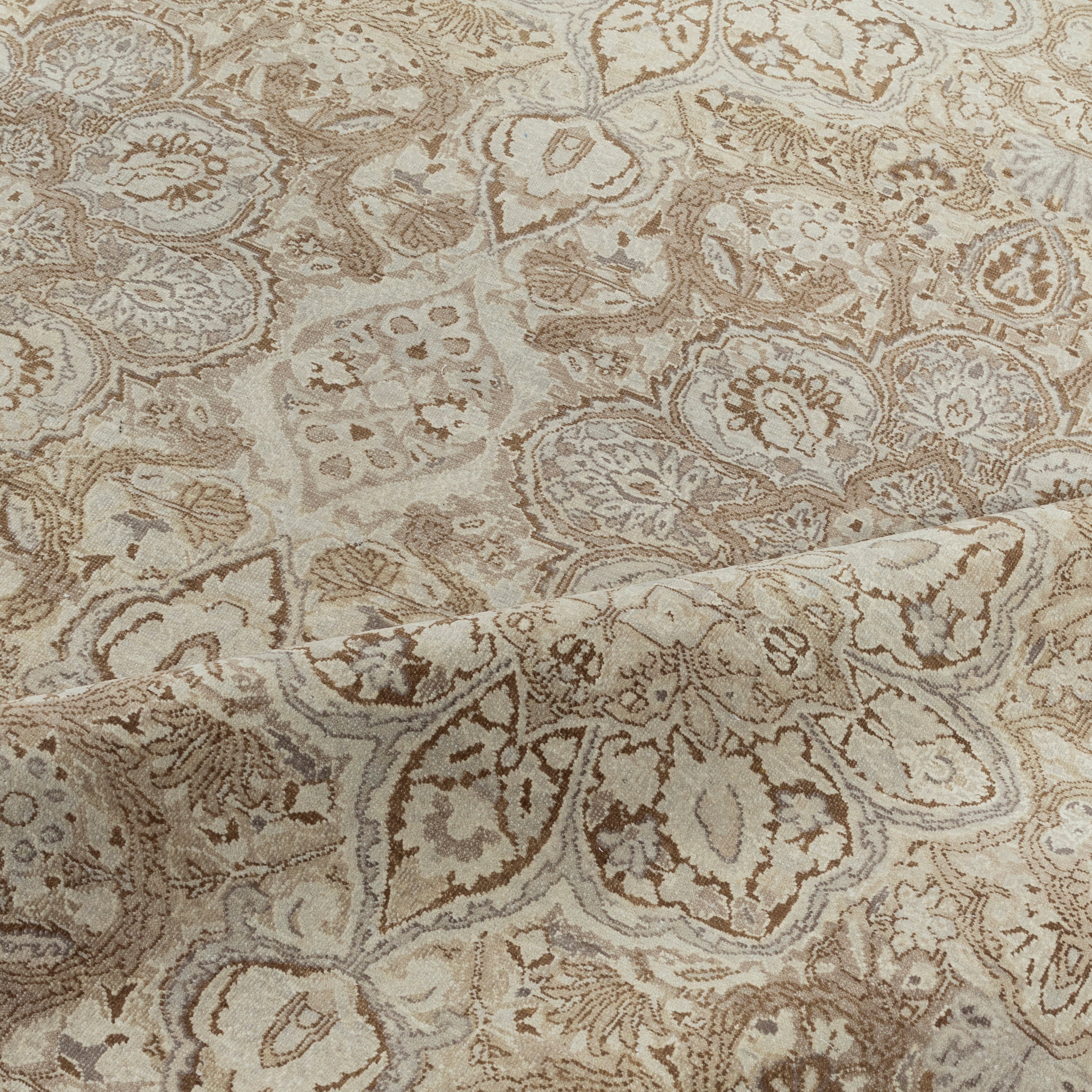 Close-up of ornate patterned carpet in beige, cream, and brown.