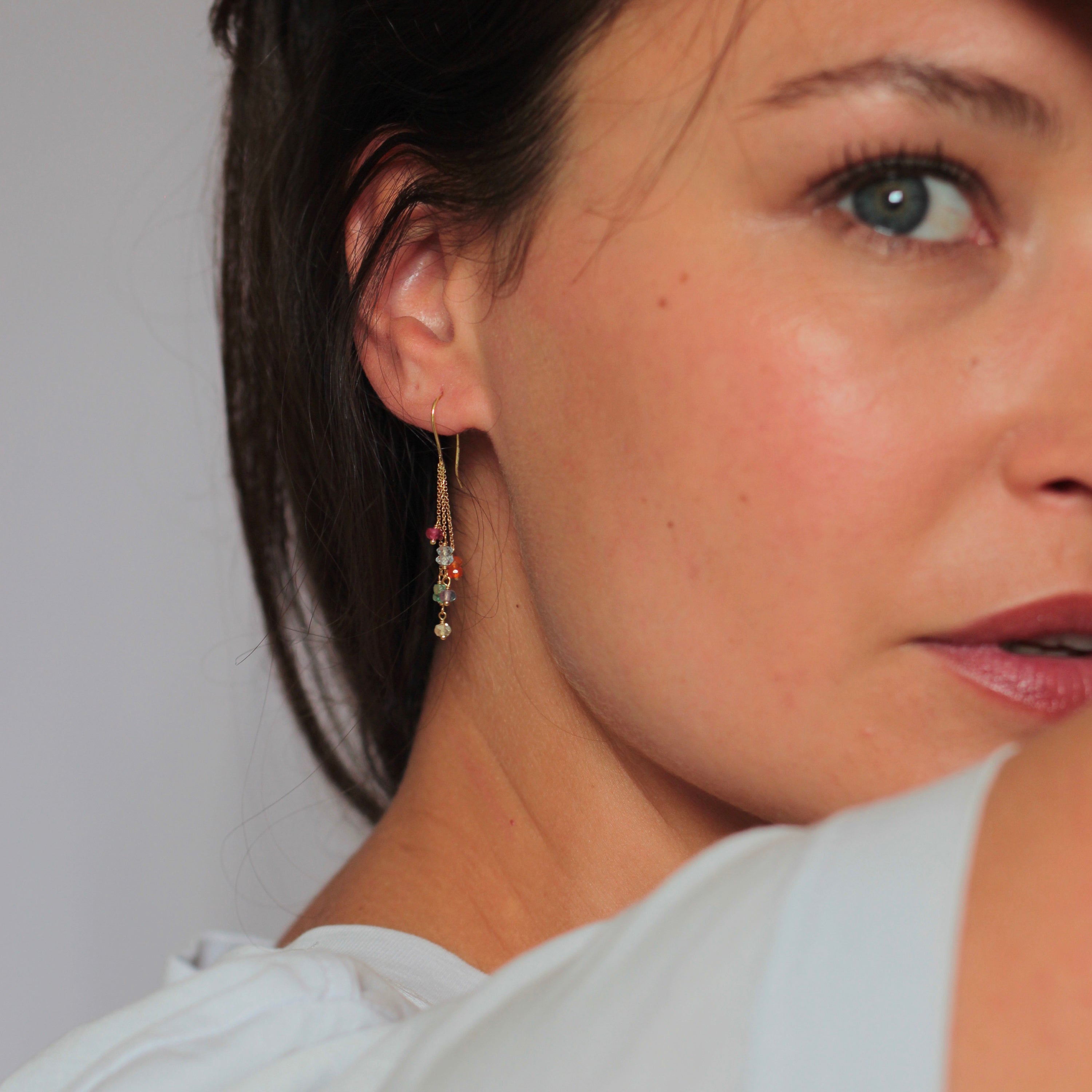 Close-up profile of person with blue eye and colorful earring.