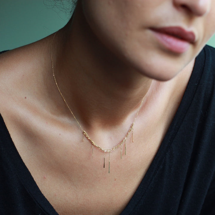 Minimalistic gold necklace on person with textured skin and collarbones.