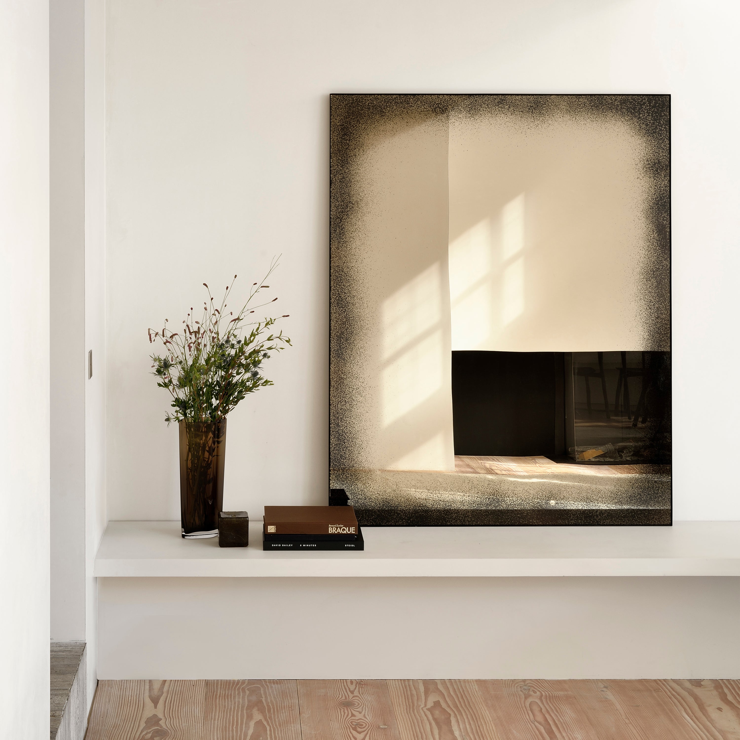 Minimalist interior with natural elements, artwork depicting light and shadow.