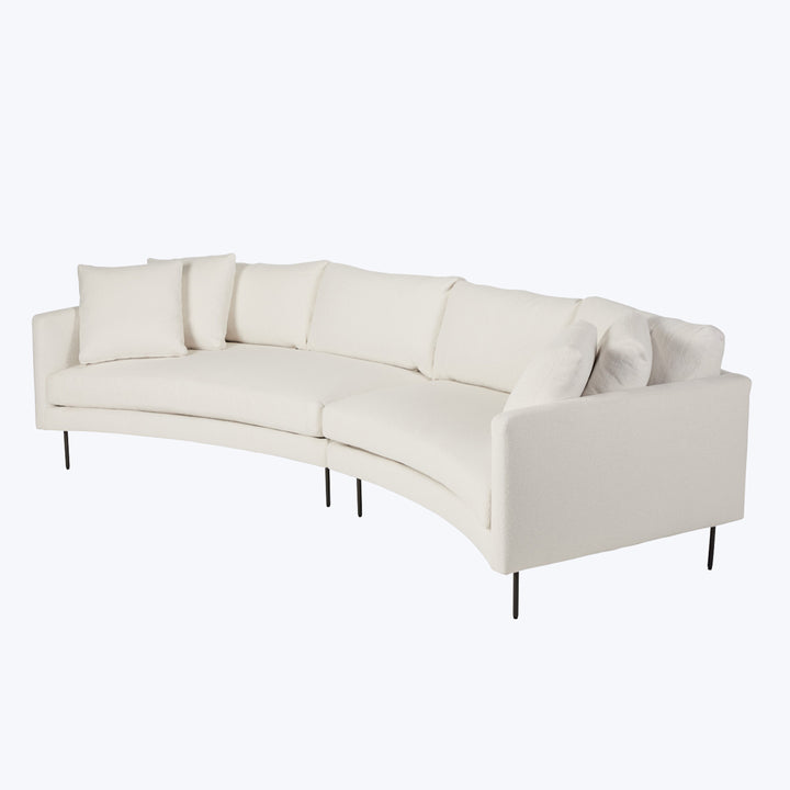 Modern curved sectional sofa with sleek design and light upholstery.