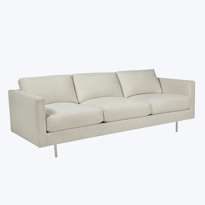 Modern three-seat sofa with neutral upholstery and sleek design.