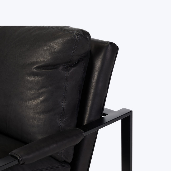 Close-up of modern black leather armchair with sleek metal frame
