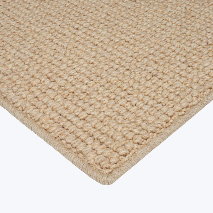 Close-up view of textured rug with woven design in neutral color.