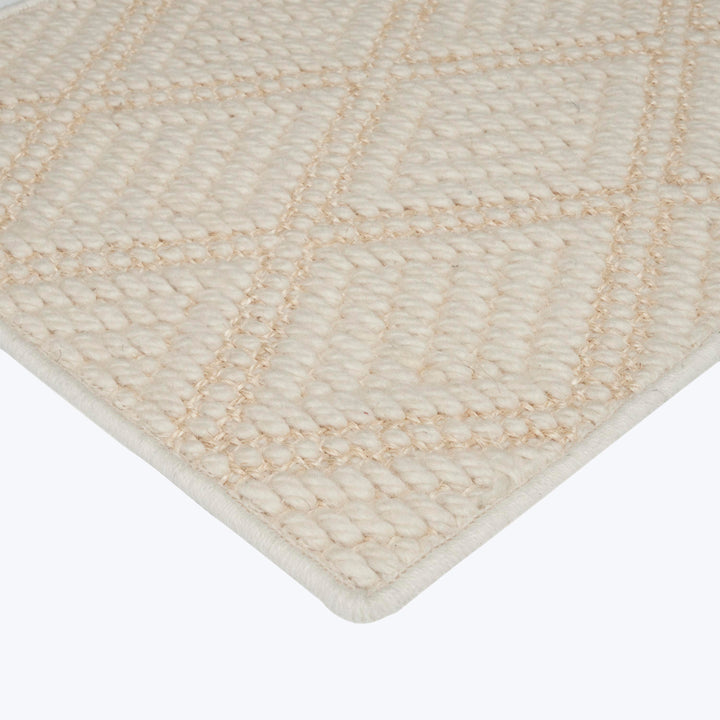 Cream-colored diamond pattern rug with plush texture and hemmed border.
