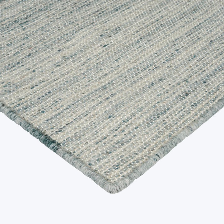 Textured flat-woven rug with mottled design and color-coordinated binding.