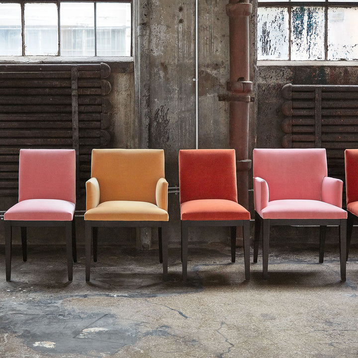 Five chairs in varying shades of red and pink indoors.
