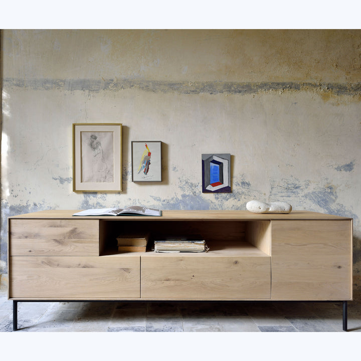 Modern wooden sideboard against textured wall with aged plaster finish.