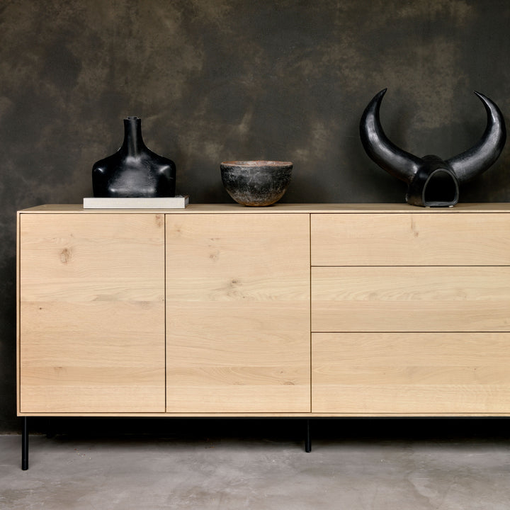 Modern minimalist sideboard with black accents and artistic decor objects.