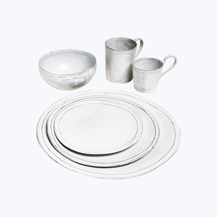 Vintage pewter tableware collection on white background: plates, bowl, cups.