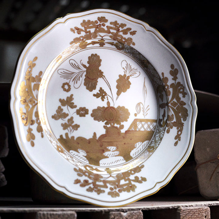 Vintage porcelain plate with intricate floral design and scalloped edge.