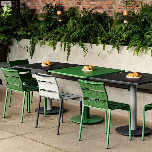 Modern outdoor dining area with chic design, green accents, and cozy ambiance.