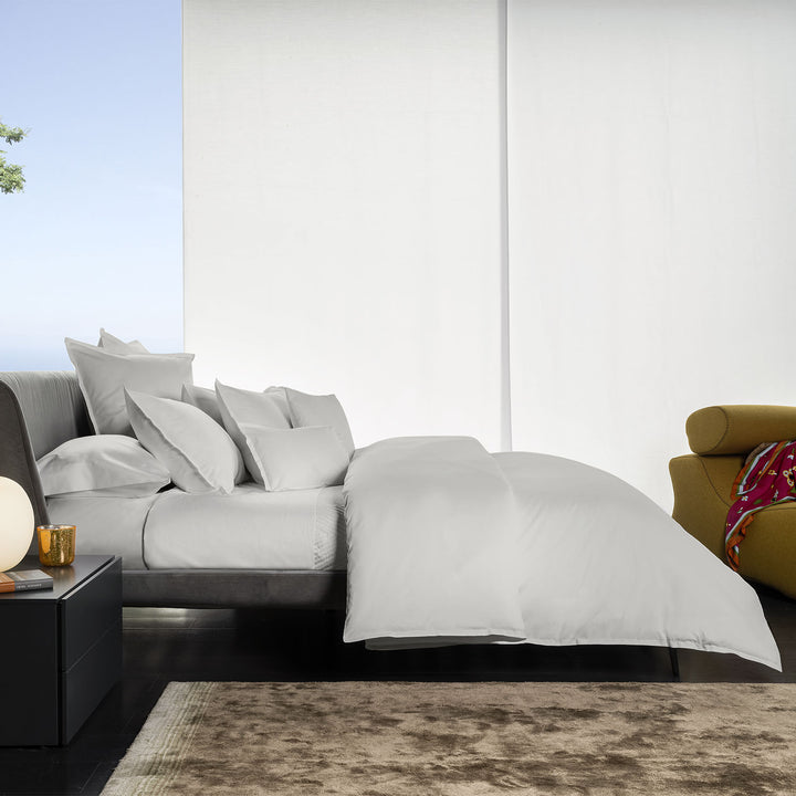 Minimalist, modern bedroom with gray bedding, plush pillows, and elegant decor.
