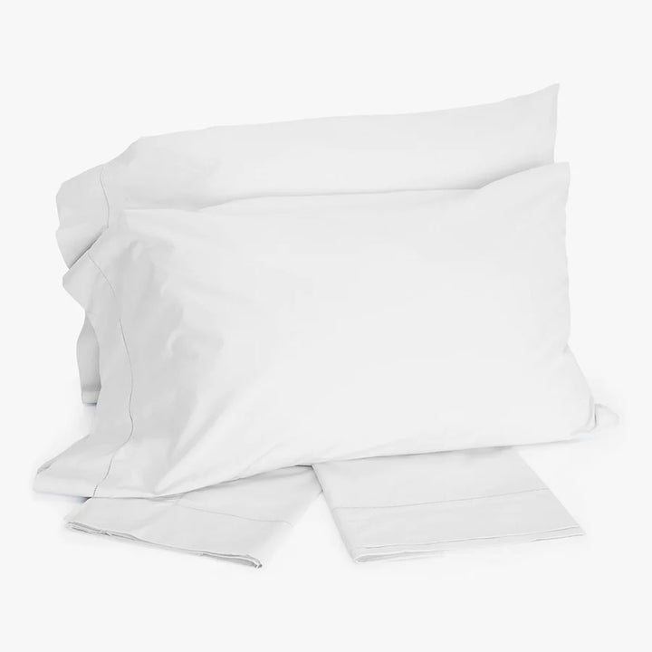 Minimalist white bedding set with pillows and folded sheets